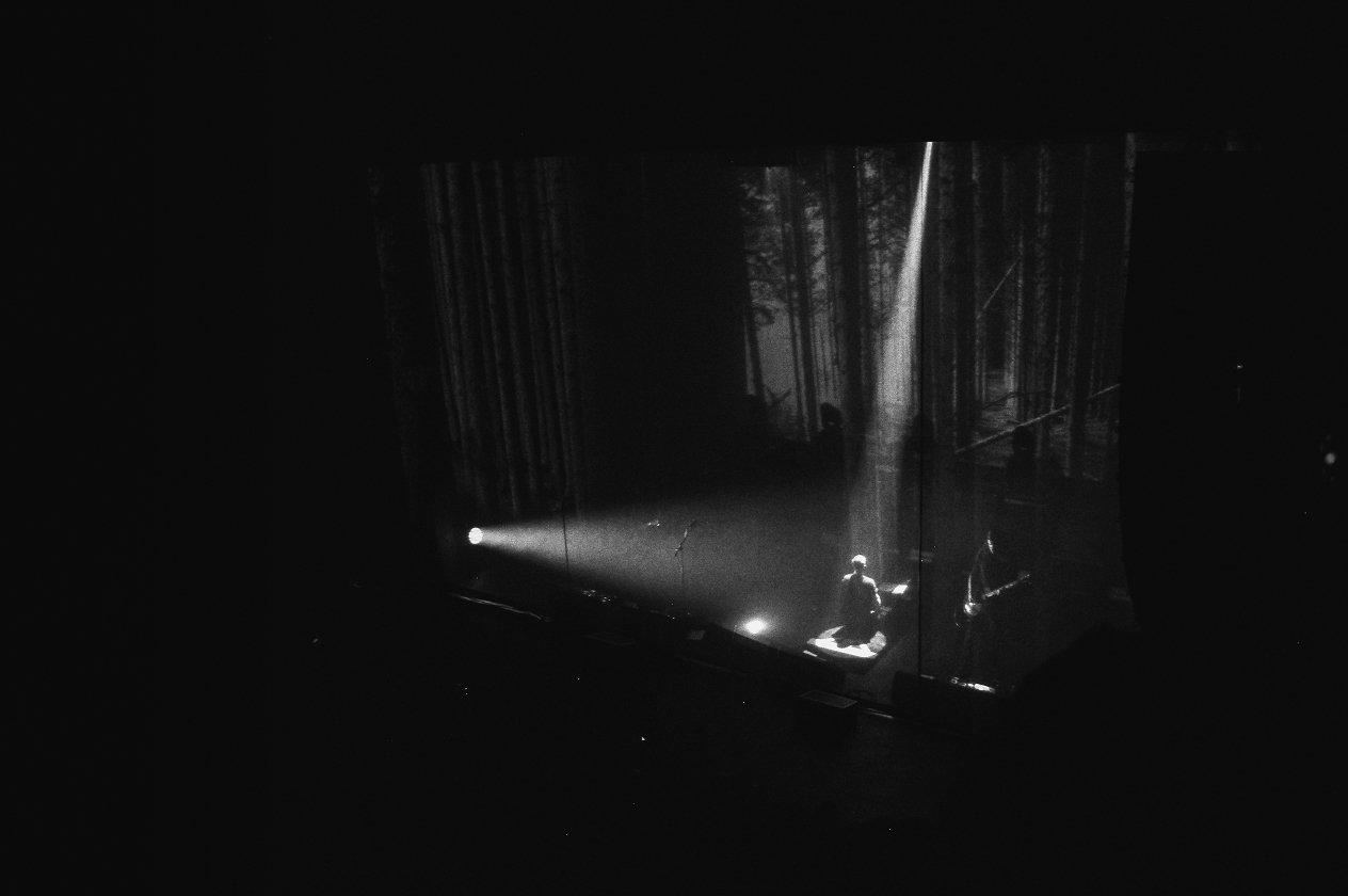 Amenra – Die Belgier zelebrieren ihre "Mass VI"-Releaseshow – mit Kunstausstellung und Körperritual. – Fronter Colin im Schattenlicht.